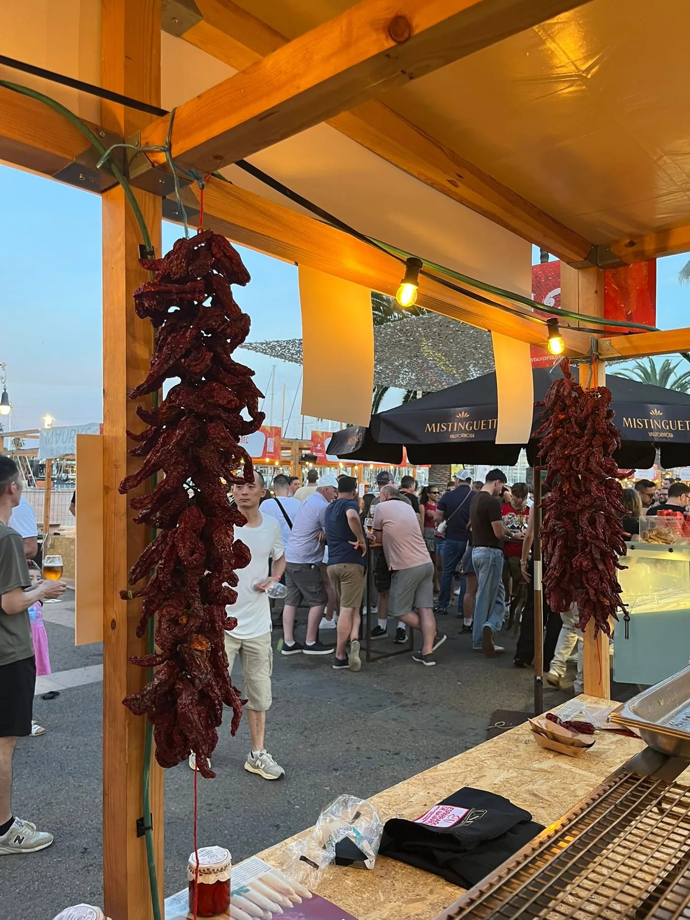 El puesto de Conservas Osés al atardecer en el Moll de la Fusta de Barcelona, con ristras de pimiento colgando